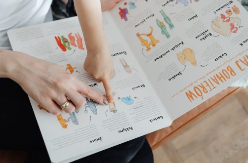 A child and adult engaging with an educational book, pointing to illustrations.